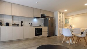 Una cocina moderna con horno empotrado, refrigerador y un comedor con mesa y sillas.