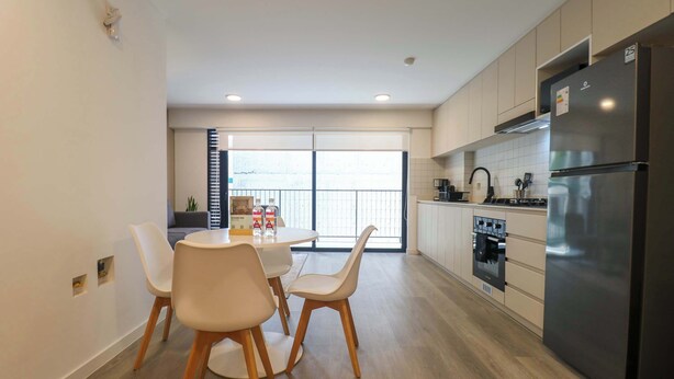 Una cocina moderna con refrigerador, horno y comedor con sillas y una mesa.