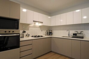 A modern kitchen with a built-in oven, a coffee maker, and a kettle on the counter. - w* | Trendy & Cozy 2BR w/ Balcony in Miraflores (Miraflores)