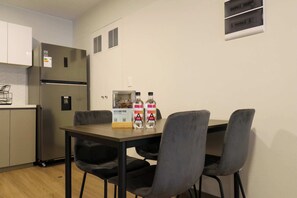 A compact kitchen with a refrigerator, a table with chairs, and two bottles of water on the table. - w* | Trendy & Cozy 2BR w/ Balcony in Miraflores (Miraflores)