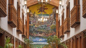 A corridor with a mural, wooden balconies, terracotta floor tiles, and potted plants. - HOTEL BOUTIQUE GRAND MAYES (Pátzcuaro)