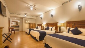 A hotel room with three beds, wooden floors, a ceiling fan, and a small kitchenette. - HOTEL BOUTIQUE GRAND MAYES (Pátzcuaro)