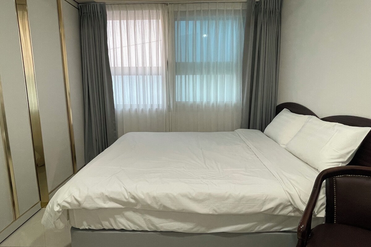 A hotel room with a bed, curtains, and a chair.