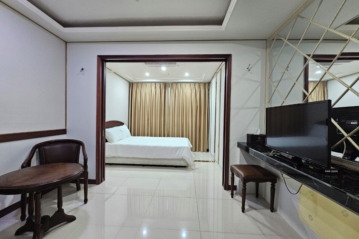 A hotel room with a bed, a TV, a desk, and a chair.