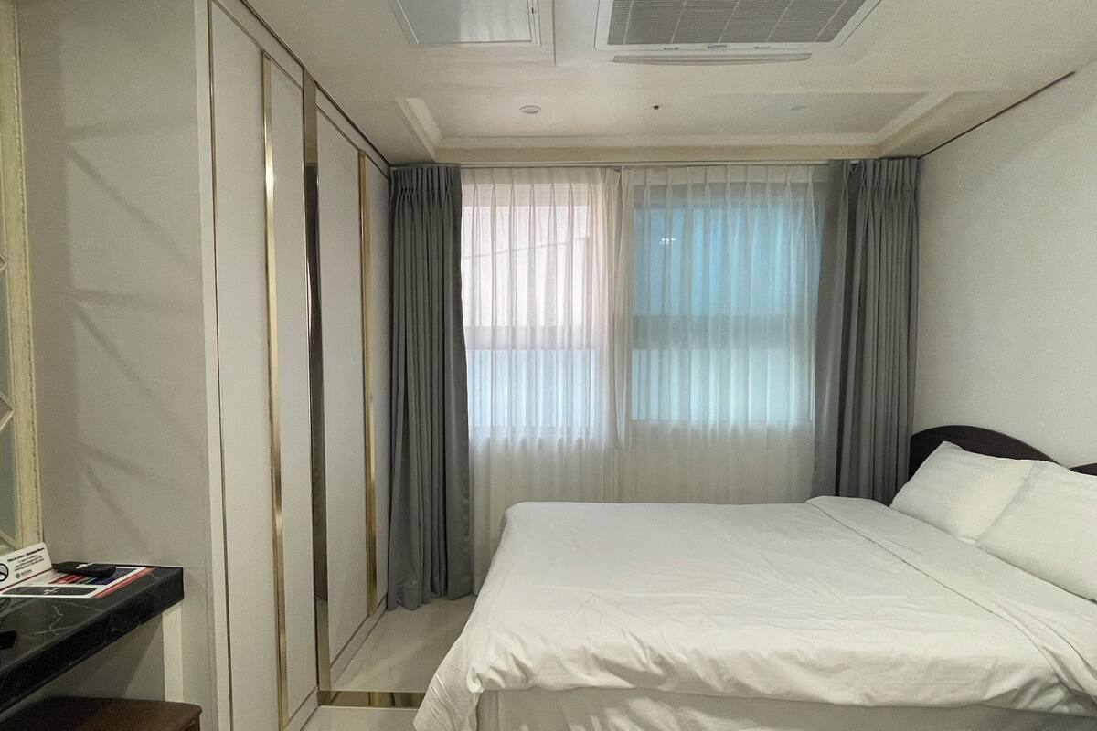 A hotel room with a bed, a desk, and a mirror.