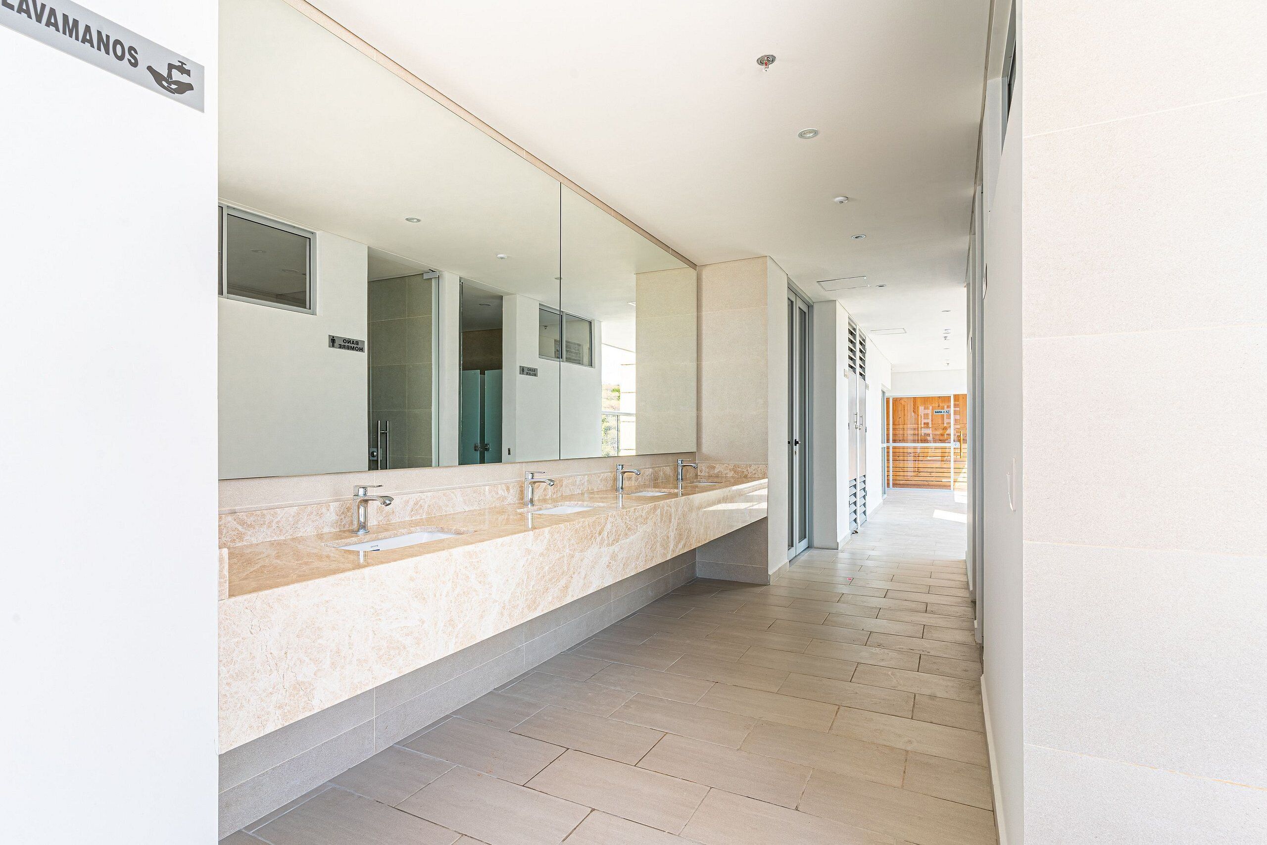 A modern bathroom with a long vanity, multiple sinks, and a large mirror.