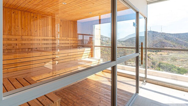 Un interior moderno con paneles de madera y ventanas amplias que ofrecen vistas a un paisaje montañoso.
