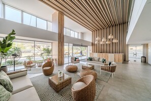 A spacious lobby with large windows, wicker furniture, and a modern ceiling design. - Salguero Suites by RV Stays (Santa Marta)