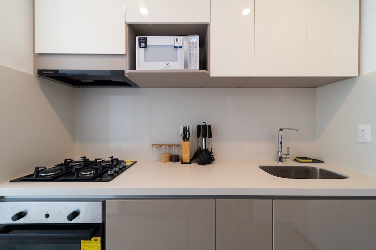 A modern kitchen with a gas stove, microwave, sink, and cabinets.
