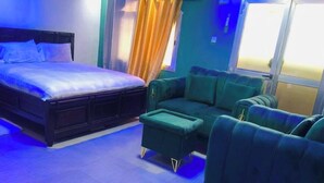 A bedroom with a bed, a green sofa, and a small table. - Serene Mountain Escape: Cozy Villa with Stunning Sunset Views (Freetown)