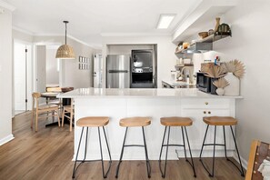 Eine moderne Küche mit einer zentralen Kochinsel, Barhocker, einem Kühlschrank und einer Mikrowelle.