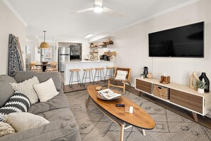 Ein modernes Wohnzimmer mit Sofa, Couchtisch und Fernseher.