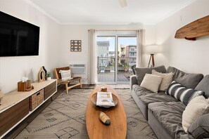 Ein modernes Wohnzimmer mit einer Couch, einem Couchtisch und einem an der Wand befestigten Fernseher.