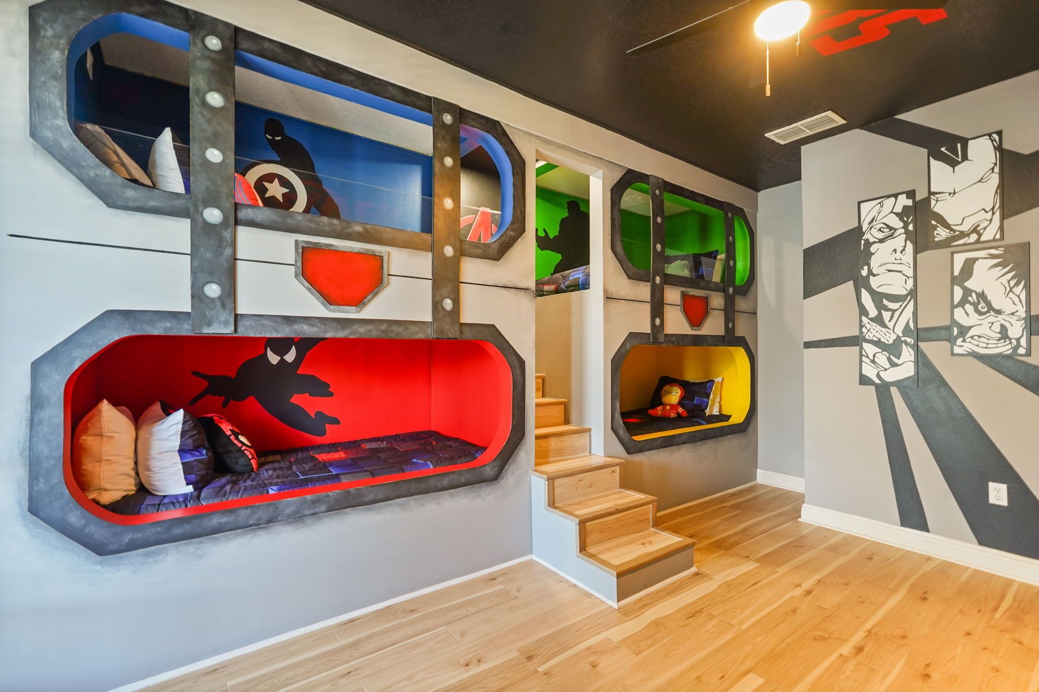 A room with a bunk bed, a staircase, and a wall with comic book-style artwork.
