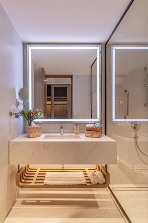 Un baño moderno con un espejo grande, un lavabo y una ducha.