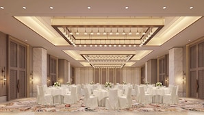 A banquet hall with round tables, chandeliers, and patterned walls.