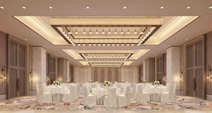 A banquet hall with round tables, chandeliers, and patterned walls.