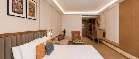 Habitación de hotel moderna con una cama grande, zona de estar y un armario.