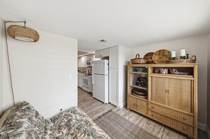 Eine kleine Küche mit weißen Schränken, einem weißen Kühlschrank und einer Mikrowelle.