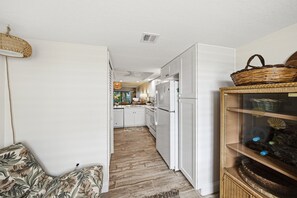 Eine Küche mit weißen Schränken, einem Kühlschrank und einem Essbereich mit Tisch und Stühlen.