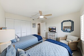 Ein Schlafzimmer mit zwei Betten, einem Fernseher, einem Deckenventilator und einem dekorativen Spiegel.
