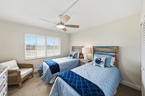 Ein Schlafzimmer mit zwei Betten, einem Deckenventilator und einem Fenster mit Jalousien.