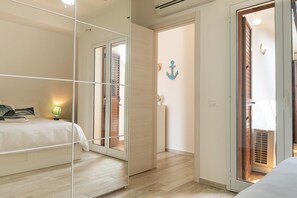 Ein Schlafzimmer mit Bett, Nachttisch, Lampe, einer Schiebetür und einer Wanddekoration.