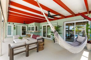 Une vaste terrasse dotée d’un hamac, de meubles d’extérieur et offrant une vue sur une piscine.
