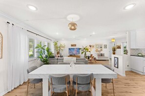 Ein modernes Wohnzimmer mit Essbereich, weißen Wänden und Holzböden.