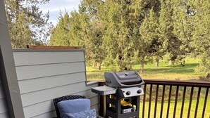 A deck with a grill, a chair with a cushion, and a water feature. - Cozy 2-bedroom townhome in Eagle Crest with AC and gym access (Redmond)