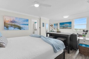 Una camera da letto con un letto, una scrivania e vista sulla spiaggia.