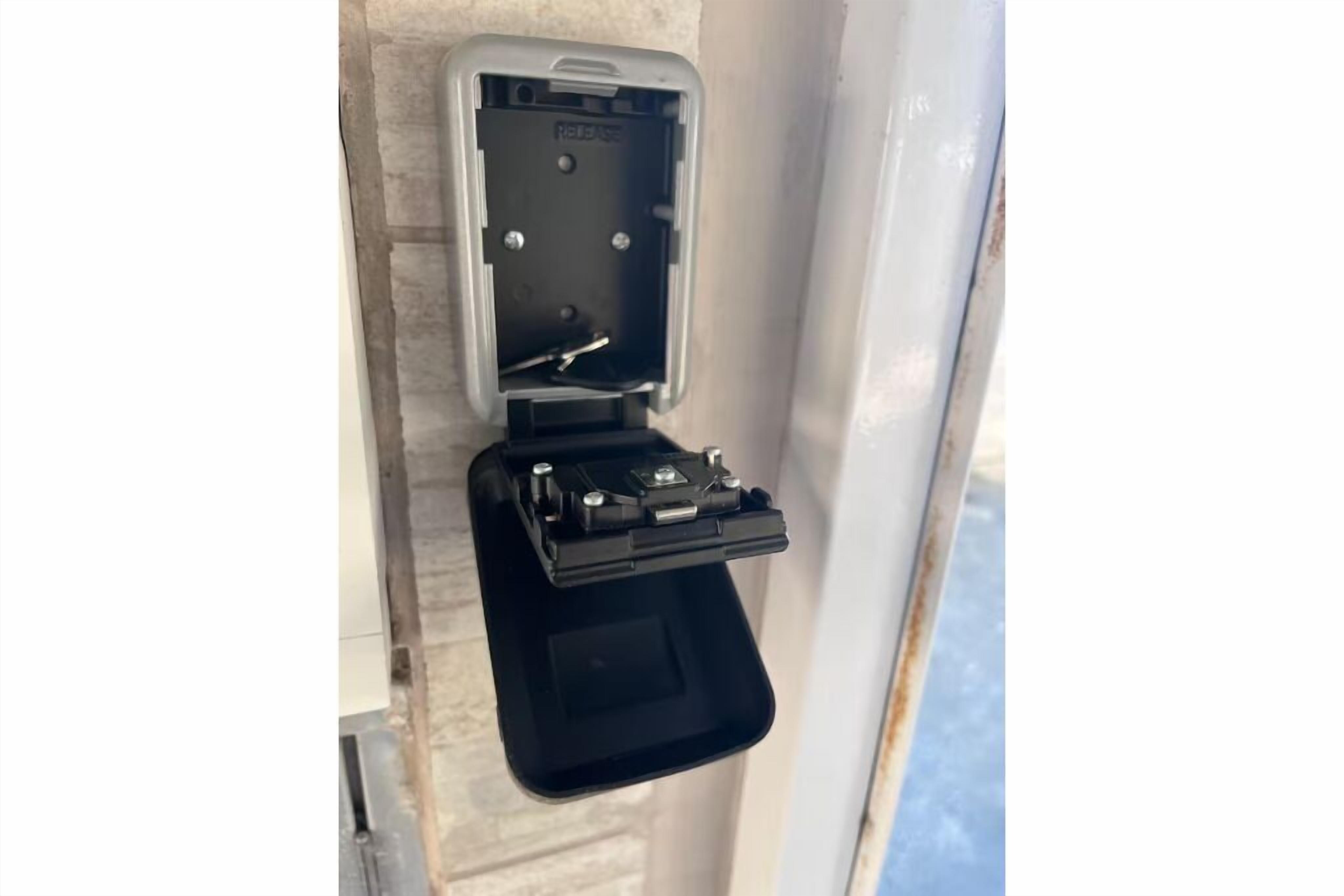 A black electrical box mounted on a wall with a metal bracket.
