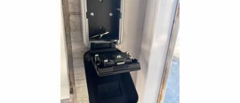 A black electrical box mounted on a wall with a metal bracket.