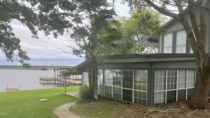 A lakeside house with a dock, a grassy lawn, and a pathway leading to the house. - Amazing 4 bed/3 bath home with a private dock, boat slip, fishing, kayaks, more (Trinity)