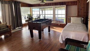 A room with wooden walls, a bed, a foosball table, and large windows. - Amazing 4 bed/3 bath home with a private dock, boat slip, fishing, kayaks, more (Trinity)