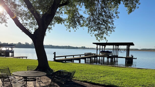 A lakeside patio with tables and chairs, a dock, and a gazebo. - Amazing 4 bed/3 bath home with a private dock, boat slip, fishing, kayaks, more (Trinity)