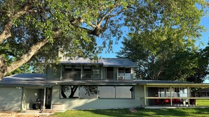 A two-story house with a front porch, a garage, and a small attached structure with outdoor seating. - Amazing 4 bed/3 bath home with a private dock, boat slip, fishing, kayaks, more (Trinity)
