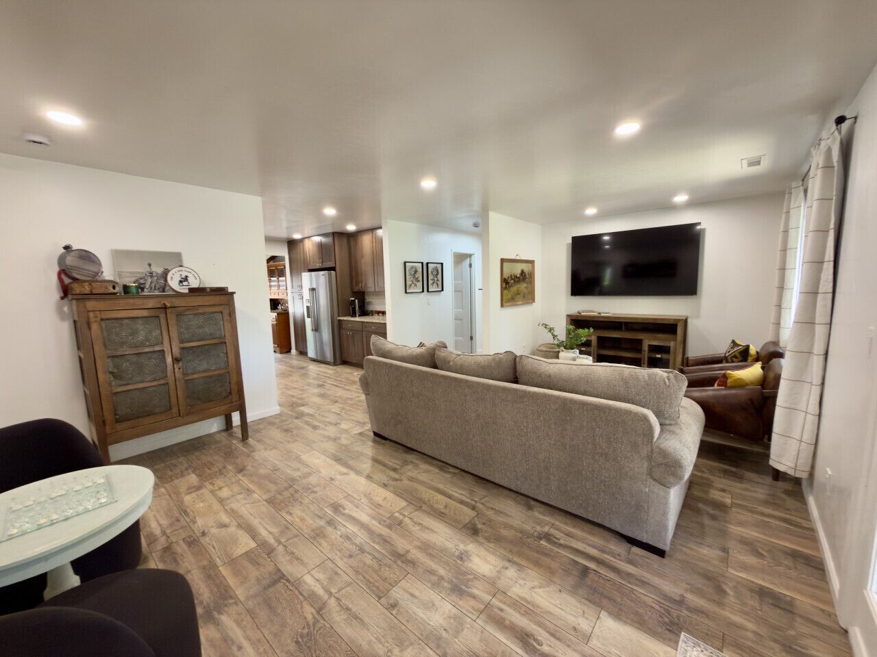 A living room with a sofa, a dining table, and a kitchen in the background.