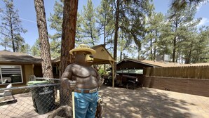 A bear statue with a hat and shorts, a trash can labeled 'City of Prescott,' and a covered area with a brick wall. - Cozy Cabin Vibes- Hot Tub- Minutes to Downtown (Prescott)