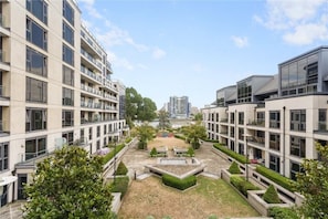 Ein moderner Apartmentkomplex mit mehreren Etagen, Balkonen und einem zentralen Innenhof mit Grünflächen.