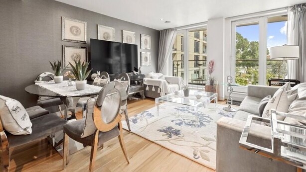 Una sala de estar moderna con comedor, ventanas amplias y un televisor de pantalla plana.