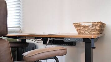 A desk with a woven basket, a chair, and a wall-mounted control panel.