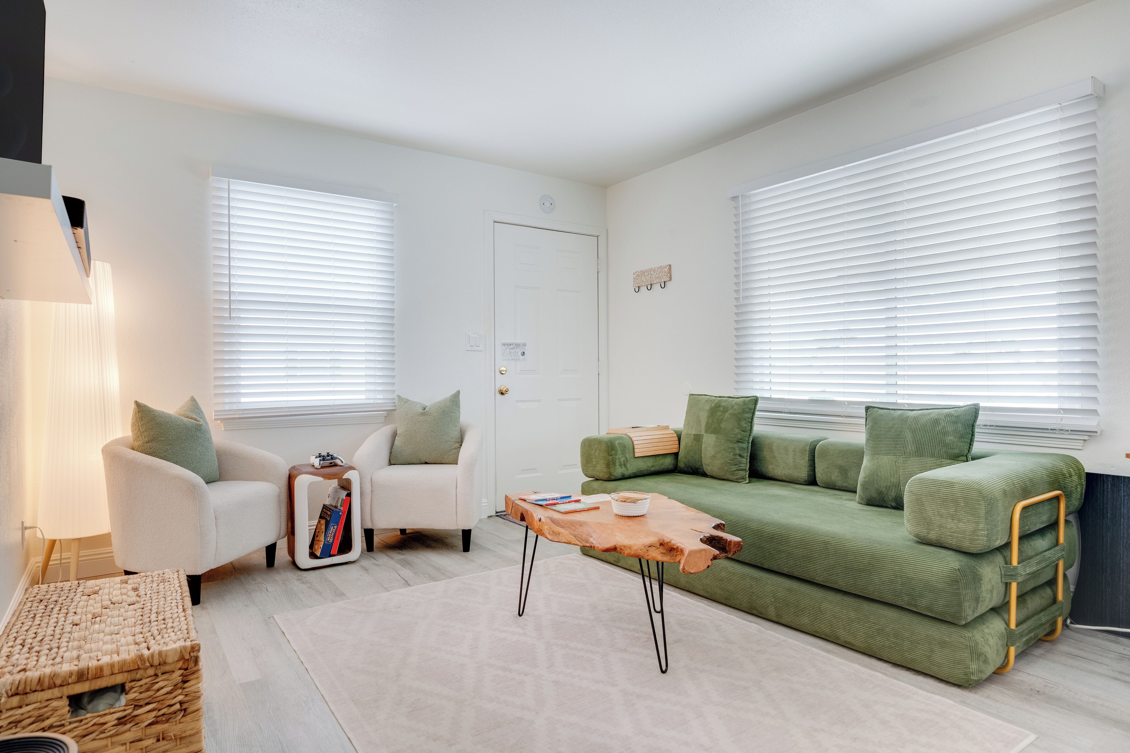 A living room with a green sofa, white armchairs, and a wooden coffee table.