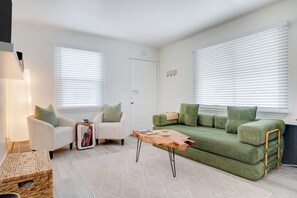 A living room with a green sofa, white armchairs, and a wooden coffee table. - Luxury San Diego 1BR with Premium Conveniences (San Diego)