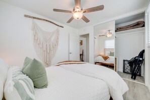 A bedroom with a bed, a ceiling fan, a macrame wall hanging, and a large mirror. - Luxury San Diego 1BR with Premium Conveniences (San Diego)