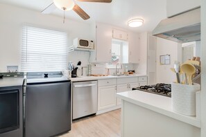 A modern kitchen with white cabinetry, a built-in microwave, a dishwasher, and a stove.