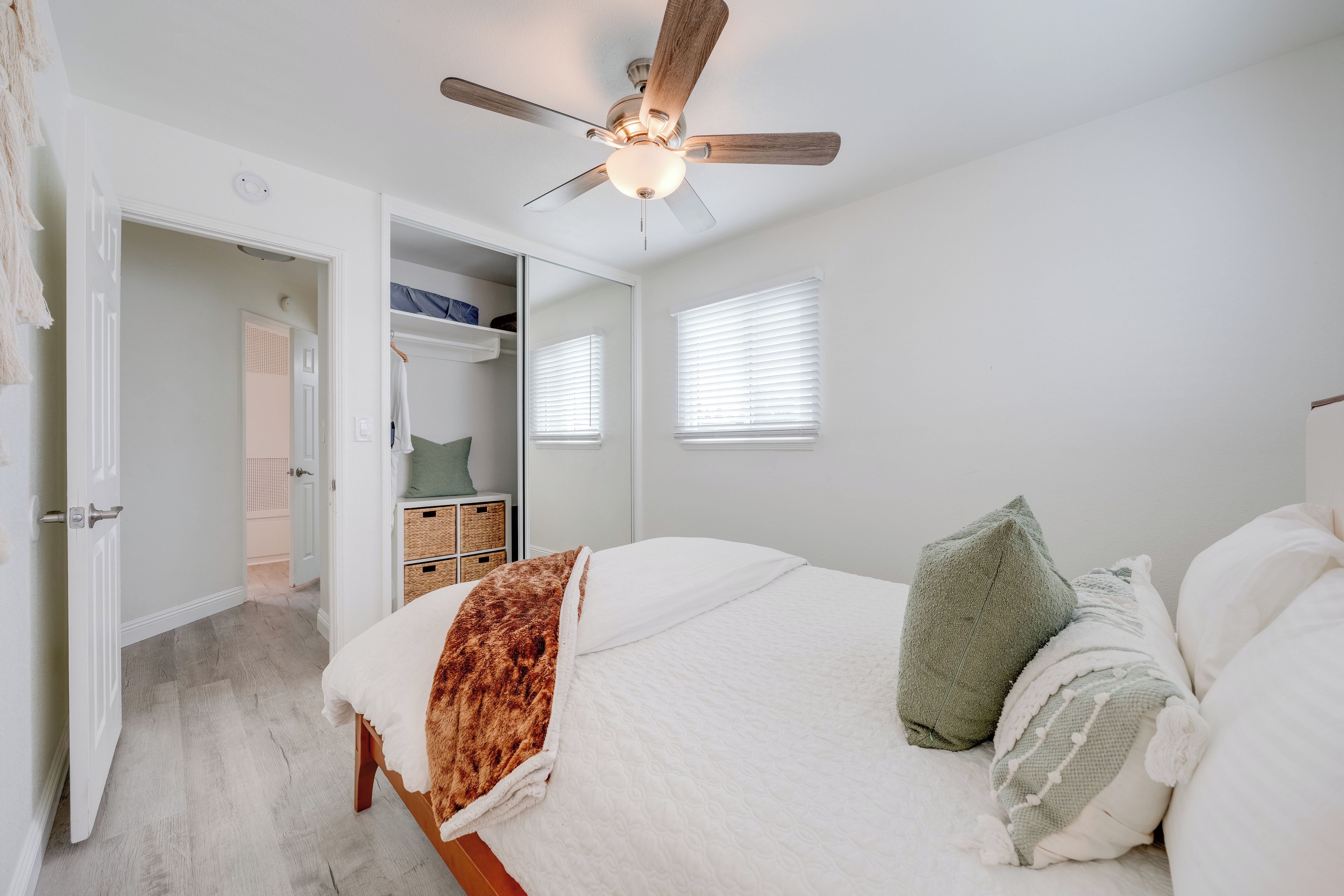 A bedroom with a bed, a ceiling fan, a closet, and a window.