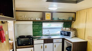 A compact kitchen with a stove, oven, microwave, and sink. - Elizabeth the spacious retro caravan. Sleeps 6 | Rye, Mornington Peninsula (Rye)
