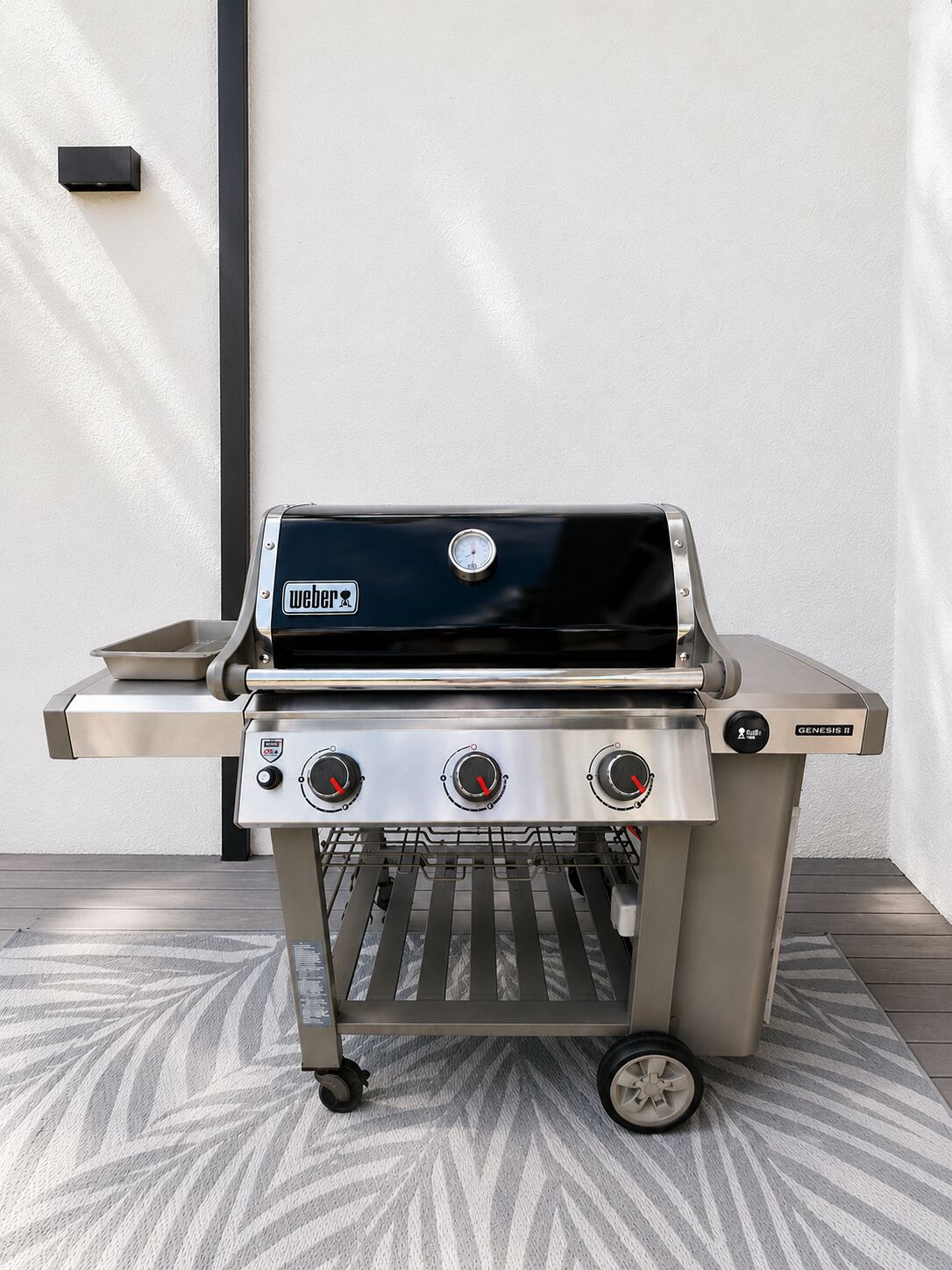 A portable Weber Genesis II grill with three burners, a digital display, and a side shelf.