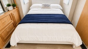 Een slaapkamer met een bed, een kaptafel, een spiegel en twee wandlampen.
